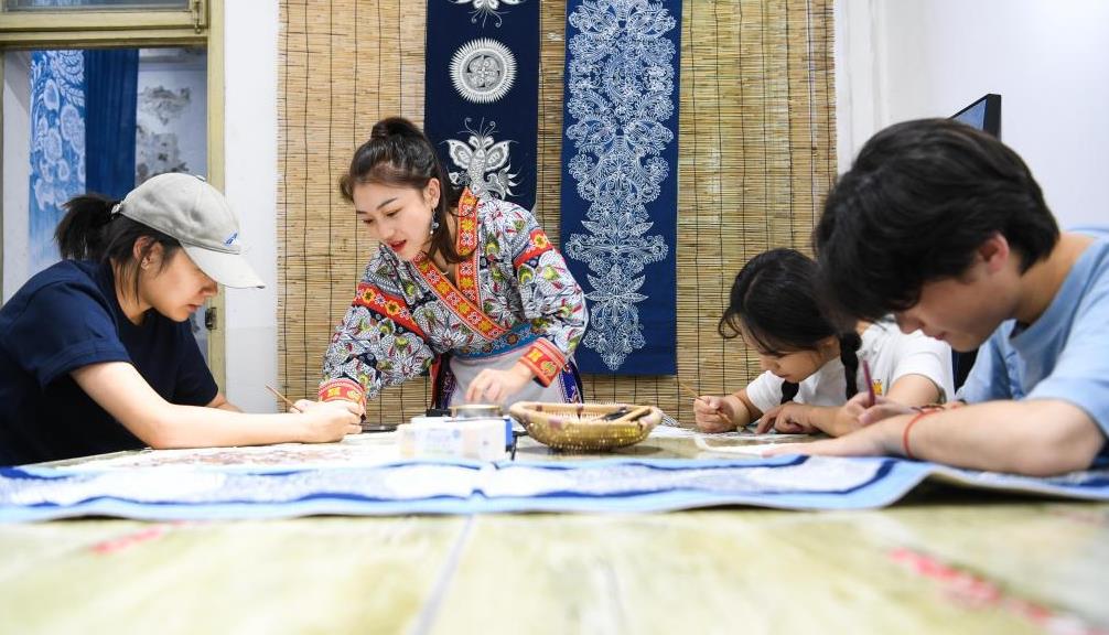 Zhang Juanjuan (zleva) instruuje příbuzné a přátele, aby kreslili voskové otisky v batikovacím studiu. Zdroj: Agentura Xinhua.